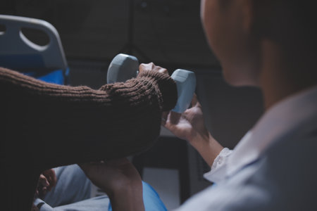 Old woman training with physiotherapist using dumbbells at home. Therapist assisting senior woman with exercises in nursing home. Elderly patient using dumbbells with outstretched arms.の写真素材