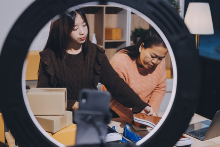 Asian woman describe selling clothes on camera live broadcast on social network at home, Online selling clothes on social media. Blogger woman influencer, SME retail store owner.の写真素材