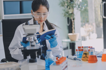 Portrait, science and happy woman on laptop in lab to research chemistry, test or innovation. Microscope, scientist and face of medical doctor in goggles for microbiology, healthcare or pharma studyの写真素材