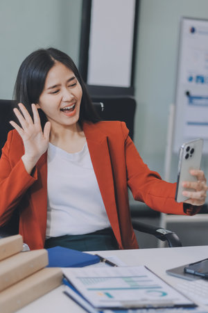 Serious woman using smartphone while working with laptopの写真素材