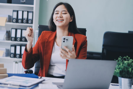 Smiling relaxed young woman sitting on couch using cell phone, happy lady holding smartphone, scrolling, looking at cellphone enjoying doing online shopping in mobile apps.の写真素材