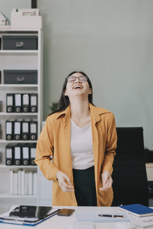 Business woman in an office setting, appearing to be engaged in work-related activities with various office items visible.の写真素材