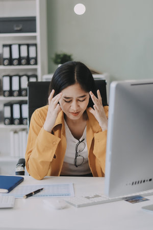 Headache, business woman at night and computer stress while working for a deadline. Sad corporate manager with anxiety about target working at desk screen late to complete task onlineの写真素材