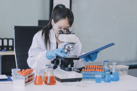 Portrait, science and happy woman on laptop in lab to research chemistry, test or innovation. Microscope, scientist and face of medical doctor in goggles for microbiology, healthcare or pharma studyの写真素材