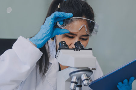 Portrait, science and happy woman on laptop in lab to research chemistry, test or innovation. Microscope, scientist and face of medical doctor in goggles for microbiology, healthcare or pharma studyの写真素材