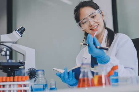 Portrait, science and happy woman on laptop in lab to research chemistry, test or innovation. Microscope, scientist and face of medical doctor in goggles for microbiology, healthcare or pharma studyの写真素材