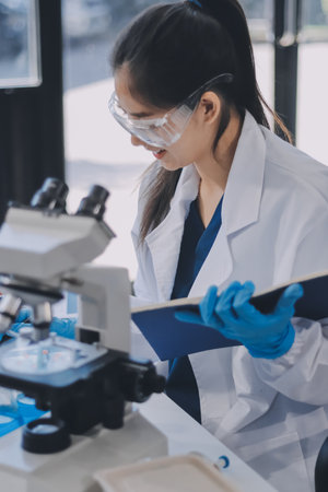 Portrait, science and happy woman on laptop in lab to research chemistry, test or innovation. Microscope, scientist and face of medical doctor in goggles for microbiology, healthcare or pharma studyの写真素材