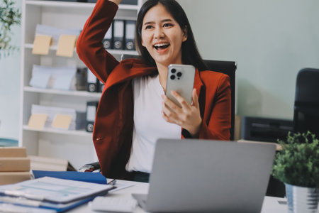 Smiling relaxed young woman sitting on couch using cell phone, happy lady holding smartphone, scrolling, looking at cellphone enjoying doing online shopping in mobile apps.の写真素材