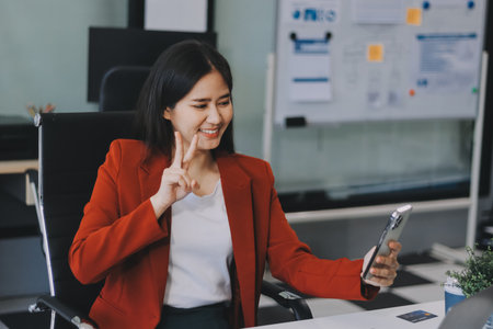 Charming woman using smartphone while working with laptopの写真素材