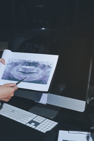 Two doctors and a female nurse meet at a table in the hospital, collaborating on medical tasks using laptops and computersの写真素材