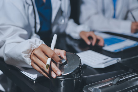 Two doctors and a female nurse meet at a table in the hospital, collaborating on medical tasks using laptops and computersの写真素材