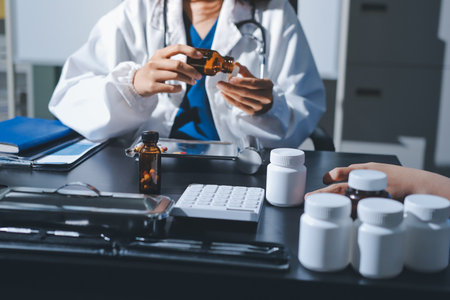 Female doctor holding a medicine bottle is checking the quality of medicine for any side effects the patient or not and recording patient information at the hospital. medical and health care conceptの写真素材
