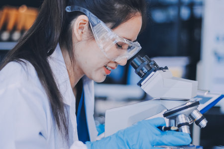 Portrait, science and happy woman on laptop in lab to research chemistry, test or innovation. Microscope, scientist and face of medical doctor in goggles for microbiology, healthcare or pharma studyの写真素材