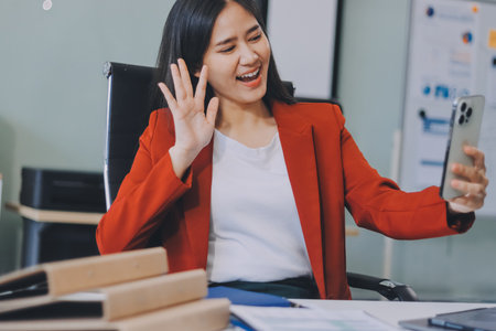 Charming woman using smartphone while working with laptopの写真素材