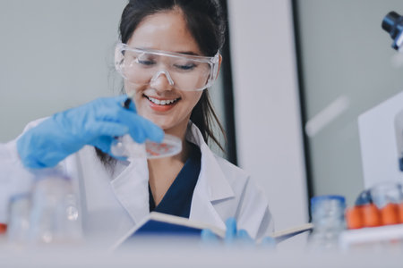 Portrait, science and happy woman on laptop in lab to research chemistry, test or innovation. Microscope, scientist and face of medical doctor in goggles for microbiology, healthcare or pharma studyの写真素材