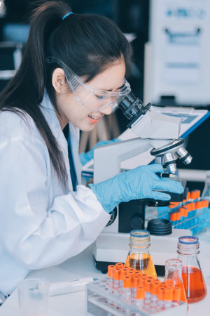 Portrait, science and happy woman on laptop in lab to research chemistry, test or innovation. Microscope, scientist and face of medical doctor in goggles for microbiology, healthcare or pharma studyの写真素材