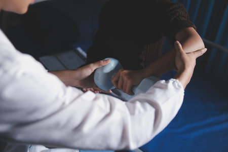 Old woman training with physiotherapist using dumbbells at home. Therapist assisting senior woman with exercises in nursing home. Elderly patient using dumbbells with outstretched arms.の写真素材