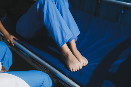 Asian male doctor examining foot of female patient sitting on bed in hospital room. Performing...