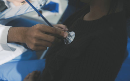 Caring doctor using stethoscope to examine patient heart during medical checkup