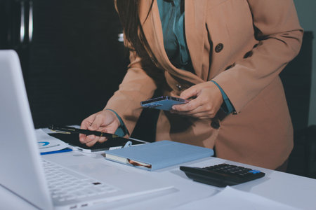 Close-up of businessman's hands making notes, mobiles, chart, desk, officeの写真素材