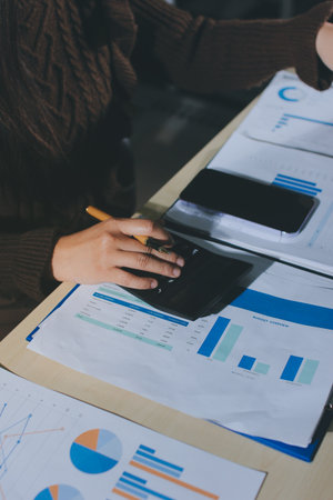 Close-up of businessman's hands making notes, mobiles, chart, desk, officeの写真素材