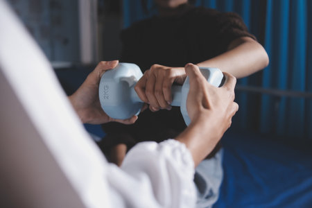 Old woman training with physiotherapist using dumbbells at home. Therapist assisting senior woman...