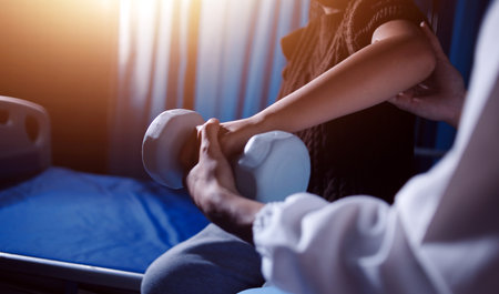 Old woman training with physiotherapist using dumbbells at home. Therapist assisting senior woman...