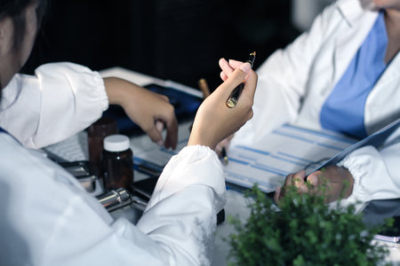 Medical team having a meeting with doctors in white lab coats and surgical scrubs seated at a table...