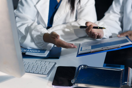 Medical team having a meeting with doctors in white lab coats and surgical scrubs seated at a table...