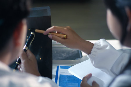 Medical team having a meeting with doctors in white lab coats and surgical scrubs seated at a table...