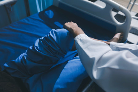 Asian male doctor examining foot of female patient sitting on bed in hospital room. Performing medical checkup. Diagnosing injury. Providing healthcare. Podiatry. Physical therapy. And rehabilitationの写真素材
