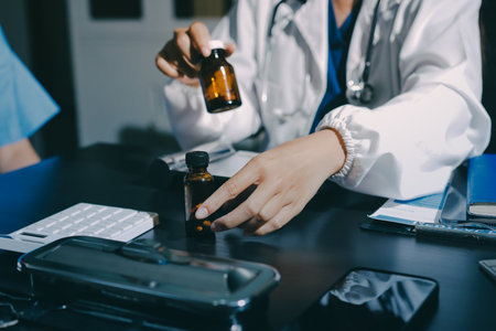Female doctor holding a medicine bottle is checking the quality of medicine for any side effects the patient or not and recording patient information at the hospital. medical and health care conceptの写真素材