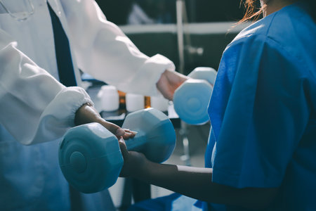 Physical therapist assisting a woman with dumbbell exerciseの写真素材