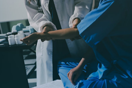 Doctor examining patient's elbow in hospital roomの写真素材