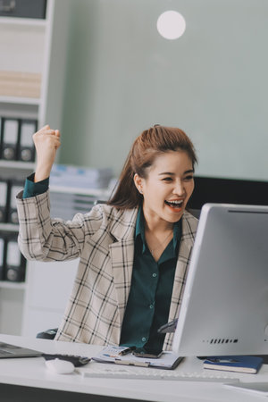 Determined asian businesswoman works late in a modern office, confidently analyzing data on her...
