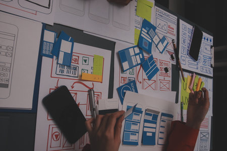 Team of uxui designers pointing at computer screen, discussing new mobile app design in the office