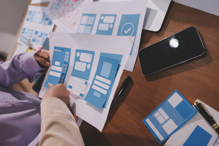 Close up ux developer and ui designer brainstorming about mobile app interface wireframe design on...