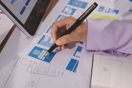 Close up ux developer and ui designer brainstorming about mobile app interface wireframe design on...