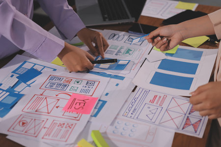 Close up ux developer and ui designer brainstorming about mobile app interface wireframe design on...