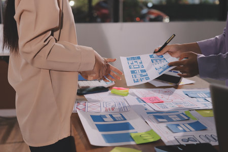 Close up ux developer and ui designer brainstorming about mobile app interface wireframe design on...