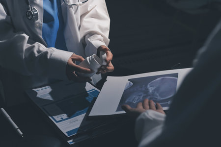 Two doctors and a female nurse meet at a table in the hospital, collaborating on medical tasks using...