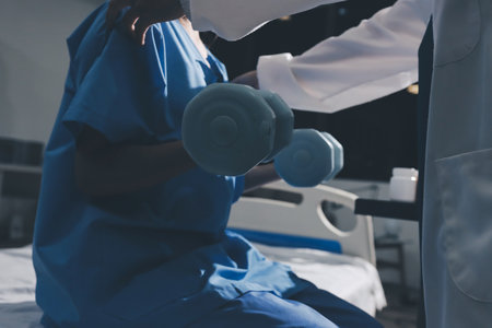 Physical therapist assisting a woman with dumbbell exerciseの写真素材