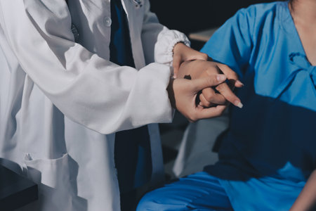 Doctor examining patient's elbow in hospital roomの写真素材