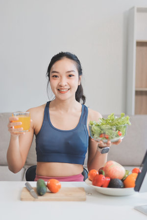Fit young Asian women in activewear sitting on yoga mat and eating fresh vegetable salad after workout, representing clean eating, fitness lifestyle, wellness routine and health balance.の写真素材