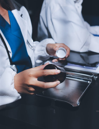 Two doctors and a nurse meet at a table, collaborating on tasks using laptops and computers