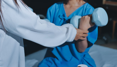 Physical therapist assisting a woman with dumbbell exercise