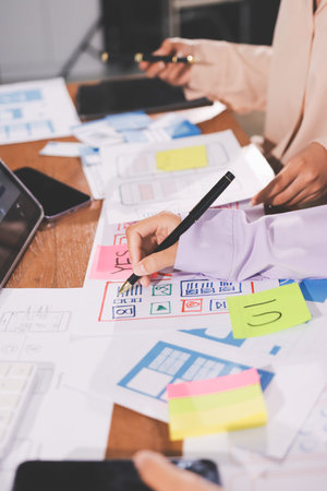 Close up ux developer and ui designer brainstorming about mobile app interface wireframe design on...