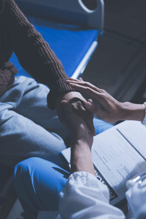 A female nurse caregiver holds hands to encourage and comfort an elderly woman. For care and trust in nursing homes for people of retirement age Caregiver helping elderly woman provides medical adviceの写真素材