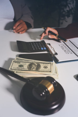 Judge gavel with Justice lawyers having team meeting at law firm in background. Notary with client in officeの写真素材