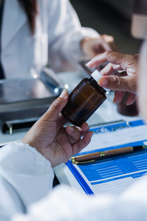 Medical team having a meeting with doctors in white lab coats and surgical scrubs seated at a table discussing a patient's case using computers in the medical industry.の写真素材